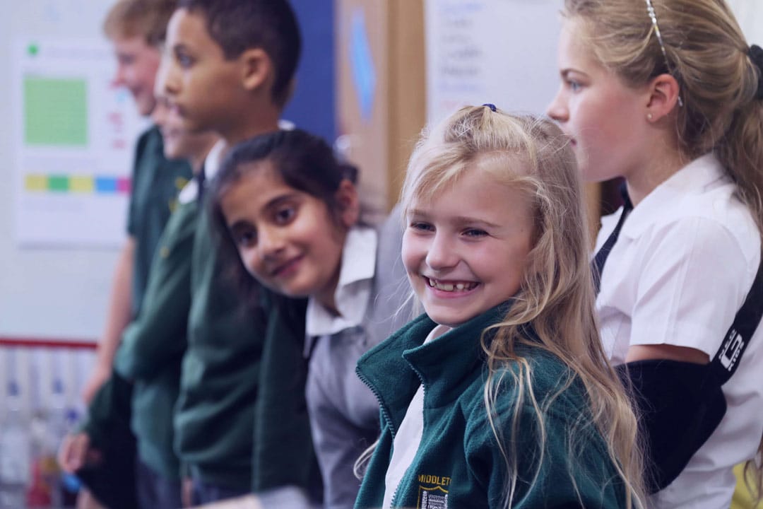 School children laughing in the classroom wearing school uniform.